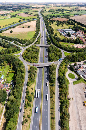 Aerial vertical panorama directly above a busy road intersection cutting through countryside on the M62 motorway heading East towards Hull in the UKの写真素材