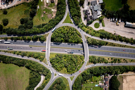 Aerial view directly above a busy road intersection on a British motorway with overbridge and slip roads in the UK countrysideの写真素材