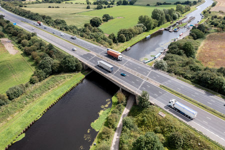 Aerial view directly above a busy UK motorway passing over a river or canal bridge in the countrysideのeditorial素材