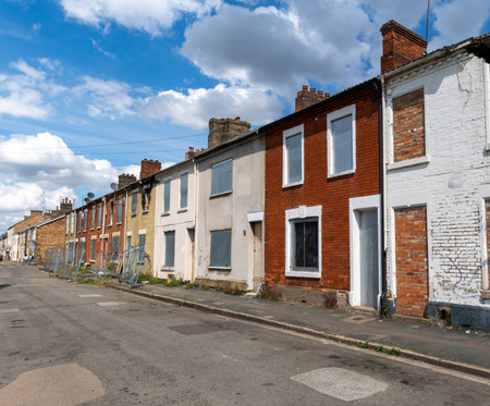 A row of burnt out and derelict terraced houses in the North of England with boarded up windows, doors and fire damaged roofs awaiting demolishion and regenerationの写真素材