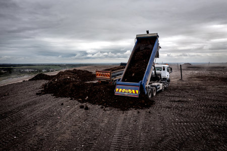 A dumper truck unloading waste at a large waste dump with tailgate raised and unloading shredded waste at a landfill site with copy spaceの写真素材