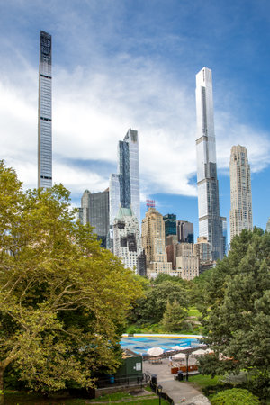 The tall skyscrapers of Midtown Manhattan framed by the green trees and green hills of Central Park in New York cityの写真素材
