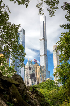 The tall skyscrapers of Midtown Manhattan framed by the green trees and green hills of Central Park in New York cityの写真素材