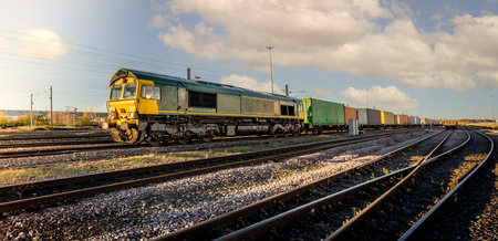 Profile view of a goods train with Intermodal wagons full of shipping container boxes for import and export in a yard or sidingsの写真素材