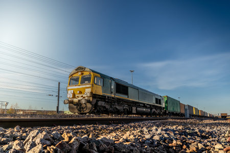 Profile view of a goods train with Intermodal wagons full of shipping container boxes for import and export in a yard or sidingsの写真素材