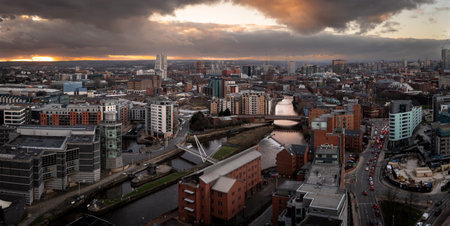 An aerial panoramic view of Leeds cityscape skyline with Leeds Dock and the River Aire running through the city with dramatic sky at sunriseの写真素材