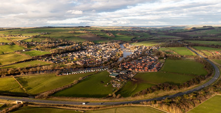 An aerial panoramic landscape of the village of Haydon Bridge in the Northumberland National Park with the River Tyne running through and A69 road bypassの写真素材