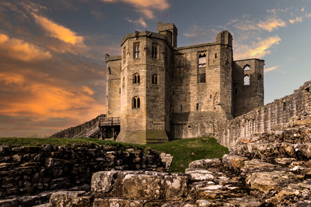 WARKWORTH CASTLE, NORTHUMBERLAND, UK - MARCH 16, 2024.  The fortified cross shaped Keep of Warkworth Castle and ruins with dramatic sky at sunsetのeditorial素材