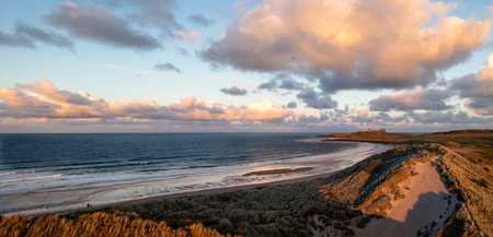 Aerial panorama landscape view of sand dunes and sandy beach at  Embleton Bay and Dunstanburgh Castle on the England Coast Path at sunsetの写真素材