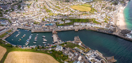 Aerial landscape of the quaint Cornish fishing town of Porthleven in Cornwall with harbour and inlet protecting a fleet of fishing boats in the popular tourist destinationの写真素材