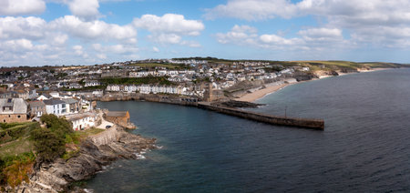 Aerial landscape of the quaint Cornish fishing town of Porthleven in Cornwall with rocky coastline and white sandy beach with harbour wall which is a popular tourist destinationの写真素材