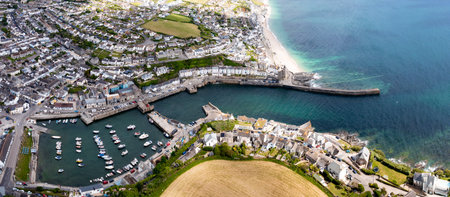 Aerial landscape of the quaint Cornish fishing town of Porthleven in Cornwall with harbour and inlet protecting a fleet of fishing boats in the popular tourist destinationの写真素材