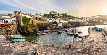 COVERACK, CORNWALL, UK - JUNE 9, 2024. Panoramic Landscape view of traditional Cornish fishing boats moored in the tidal harbour of the quaint fishing village of Coverack in Cornwall at sunsetのeditorial素材