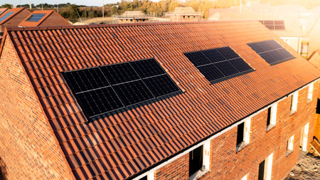 The roof of a row of new build houses on a construction site with roof integrated or In-Roof solar panels for cheap and sustainable energy in an eco friendly propertyの写真素材