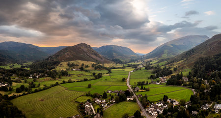 Aerial panoramic landscape of the village of Grasmere in The Lake District National Park with the A591 road running through the valley to Keswick with a beautiful sunriseの写真素材