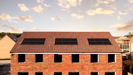 The roof of a row of new build houses on a construction site with roof integrated or In-Roof solar panels for cheap and sustainable energy in an eco friendly propertyの写真素材