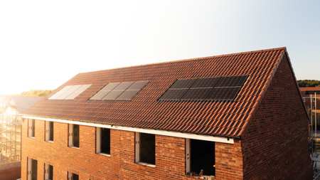 The roof of a row of new build houses on a construction site with roof integrated or In-Roof solar panels for cheap and sustainable energy in an eco friendly propertyの写真素材