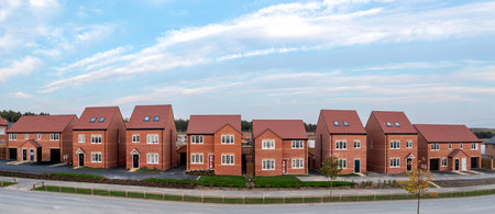 A panoramic landscape row of new build detached homes on a construction site for the UK Government's Right To Buy scheme during a new house shortage with sold signの写真素材