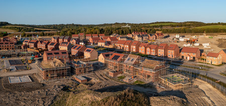 Aerial panoramic landscape view of a new build housing estate with houses under construction to fill the gap in the UK home shortage and supplement the UK Government's Right To Buy policyの写真素材