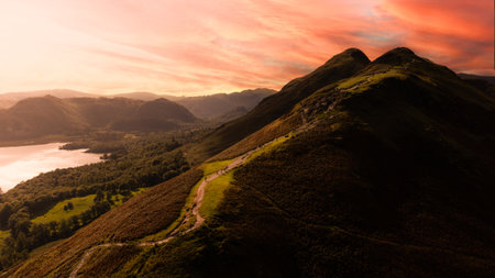 Aerial landscape view of Catbells mountain overlooking Derwent Water in The English Lake District National Park with hikers and walkers climbing the well trodden path in Autumnal sunlightの写真素材