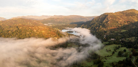 Aerial panoramic landscape of low lying mist or cloud inversion over Grasmere and Rydal Water lakes in  the Lake District National Park on a cold Autumn morning with sunriseの写真素材