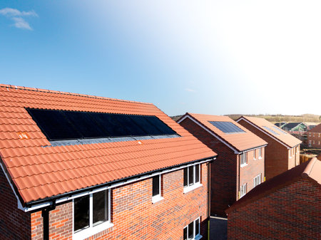 The roof of a row of new build houses on a construction site with roof integrated or In-Roof solar panels for cheap and sustainable energy in an eco friendly propertyの写真素材