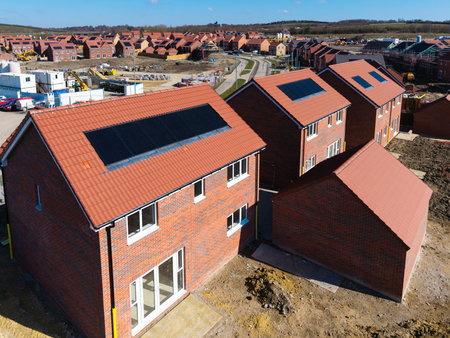 The roofs of a row of new build houses on a construction site with roof integrated or In-Roof solar panels for cheap and sustainable energy in an eco friendly propertyの写真素材