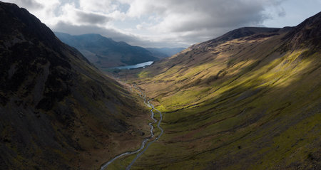Dramatic aerial panorama landscape view of the Honister Pass road in The English Lake District National Park in Cumbria, UK with surrounding mountains winding it's way to Buttermere Lakeの写真素材