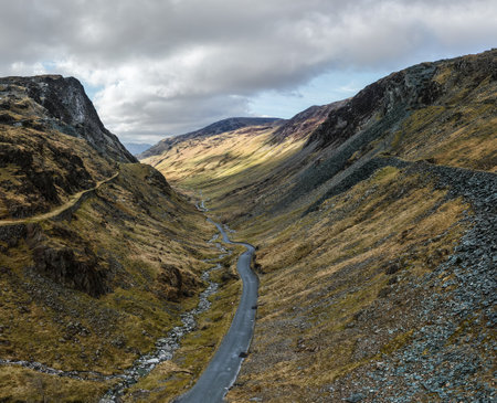 Aerial panorama landscape view of the Honister Pass road in The English Lake District National Park in Cumbria, UK with surrounding mountains winding it's way to the Honister Slate Mineの写真素材