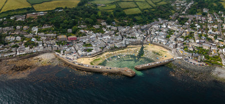 Aerial landscape view directly above of the quaint Cornish fishing village of Mousehole on the Lizard Peninsula in Cornwall with rocky coastline and historic harbourの写真素材