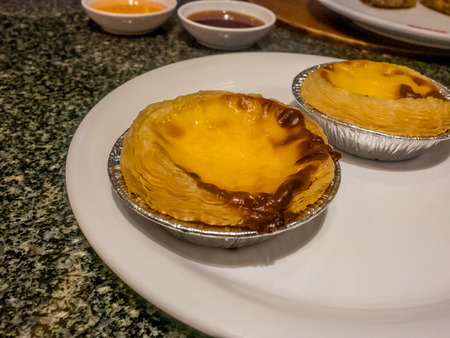Double egg tart on white dish at chinese restaurant.