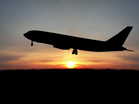 Silhouette of airplane over sunsetの写真素材