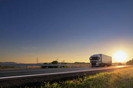 Landscape with a moving truck on the highway at sunset.の写真素材