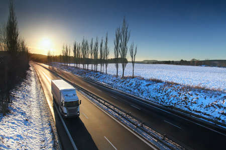 Landscape with a moving truck on the highway at sunset.の写真素材