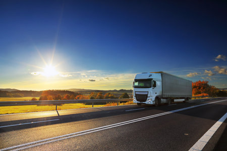Landscape with a moving truck on the highway at sunset.の写真素材