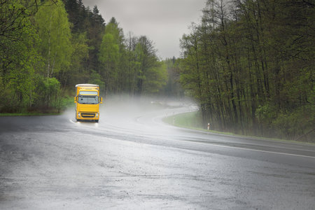 Yellow truck on the road in the forest with fog in the backgroundの写真素材