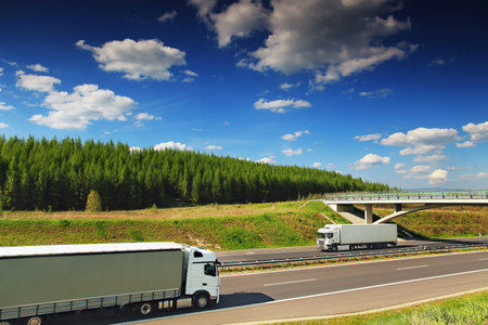 Trucks on the highway under the blue sky with white cloudsの写真素材