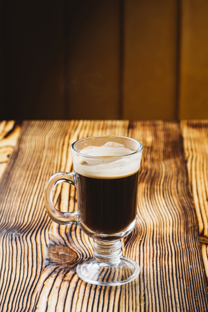 glass coffee cup on rustic textured wooden table with dark lightの写真素材