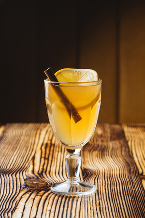 Hot white mulled wine in glass with orange on a wooden rustic tableの写真素材