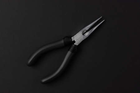 Isolated metal pliers with plastic black handles on a black backgroundの写真素材