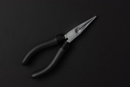 Isolated metal pliers with plastic black handles on a black backgroundの写真素材