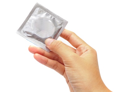Hand holding a condom on white backgroundの写真素材
