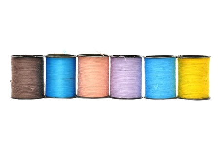 coloured bobbins thread isolated on whiteの写真素材