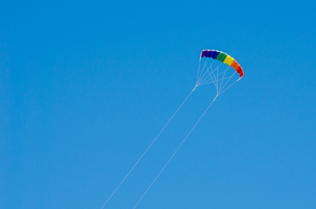 Colorful kite flying in a clear blue skyの写真素材