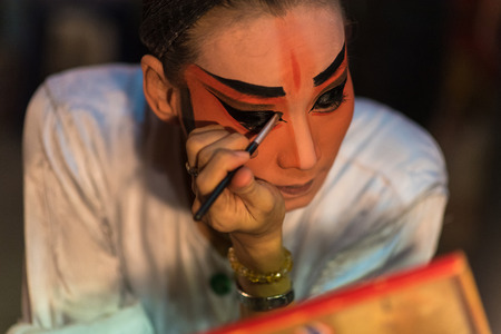 BANGKOK - OCTOBER 16: A Chinese opera actress painting mask on her face before the performance at...