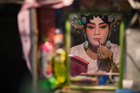 BANGKOK - OCTOBER 16: A Chinese opera actress painting mask on her face before the performance at backstage at major shrine in Bangkok's chinatown on October 16, 2015 in Bangkok,Thailandのeditorial素材