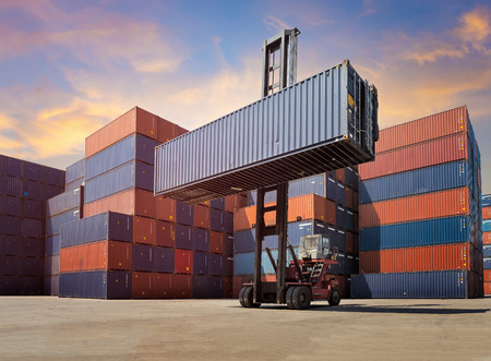Forklift truck lifting Cargo containers in shipping yard for import,export industrial against sunrise sky environment.の写真素材