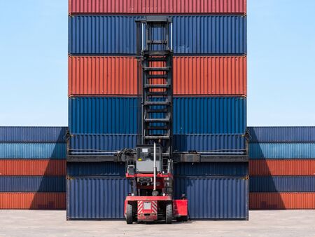 Forklift truck lifting cargo container in shipping yard for import,export, logistic industrial with container stack backgroundの写真素材