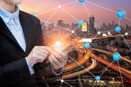 Asian business woman use smartphone technology for internet of things with Smart city with wifi connection.Photo design for smart city and smart technology internet of things conceptの写真素材