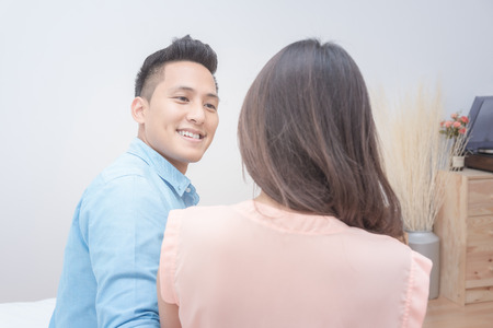 Romantic honeymoon of asian couple lovers,husband looking his wife face with sweet eyes in bedroom.の写真素材